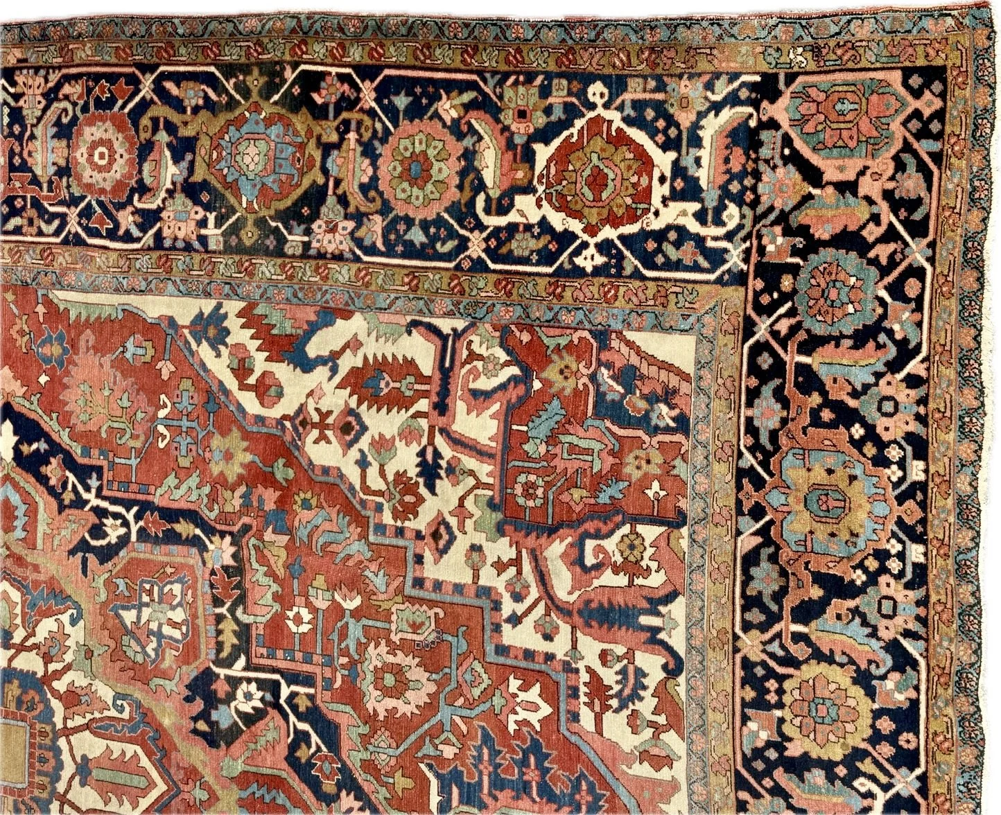 Close-up of a traditional Persian rug with intricate floral and geometric patterns in shades of red, blue, cream, and pink.