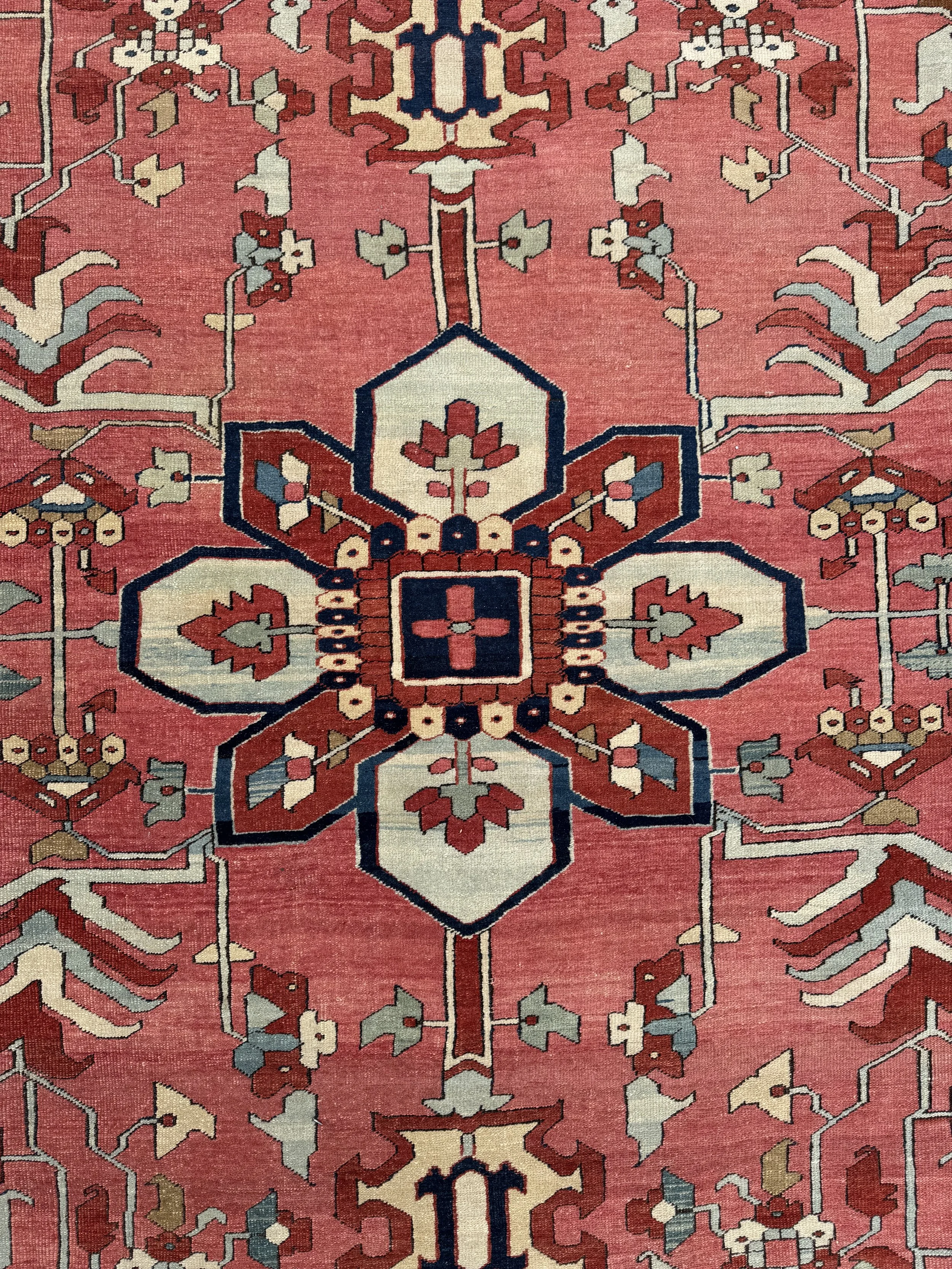 A traditional patterned rug with floral and geometric designs in red, white, blue, beige, and brown colors.