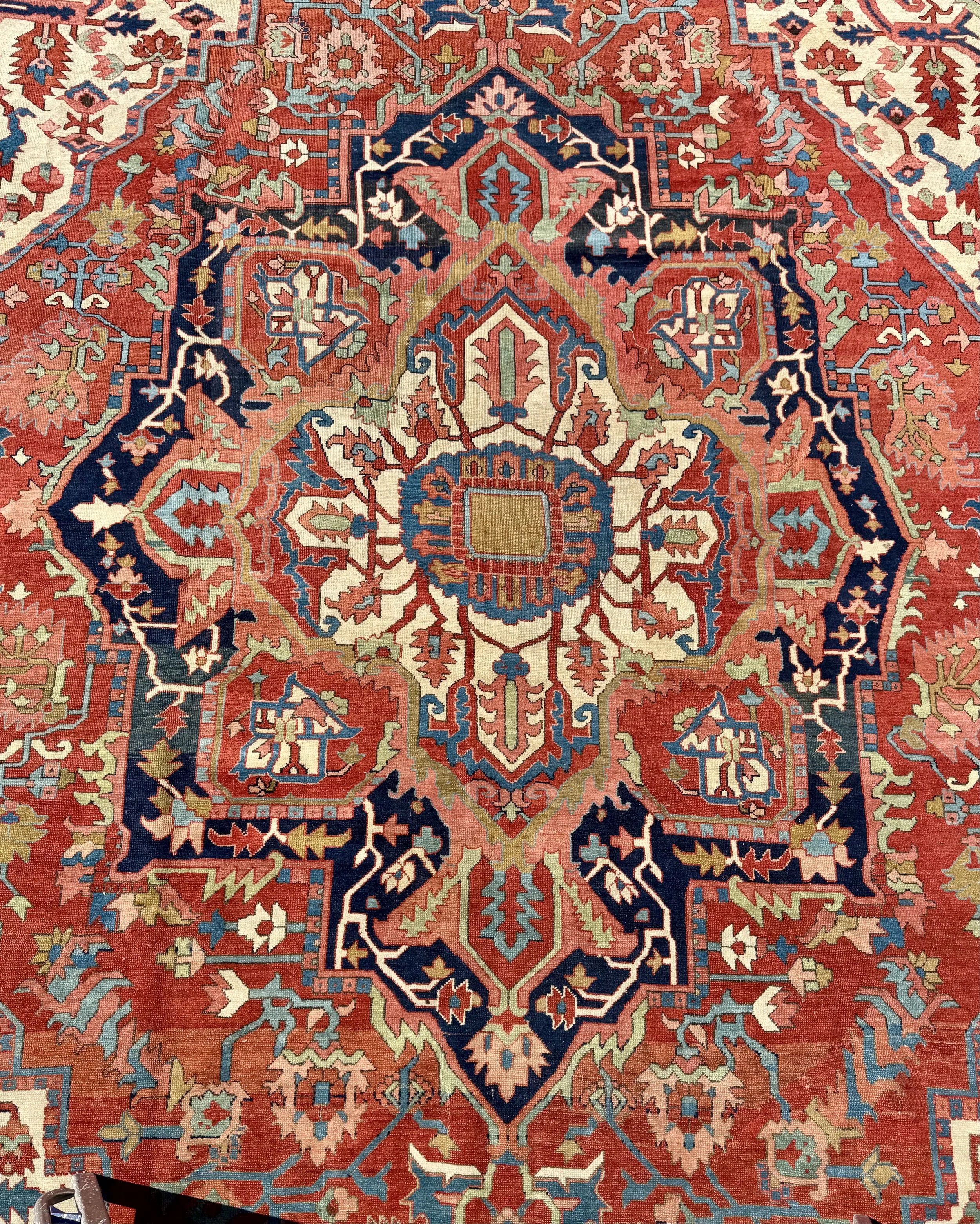 A detailed, colorful Persian-style rug with intricate traditional geometric and floral patterns in red, blue, green, white, and beige.