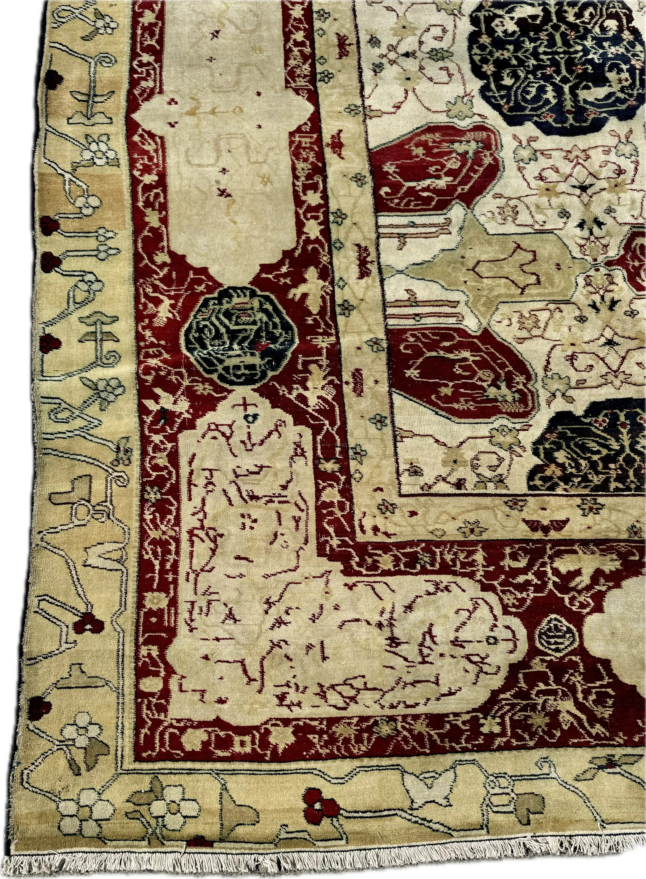 Close-up of a traditional decorative area rug with intricate patterns in red, beige, black, and white, featuring floral designs and geometric motifs.