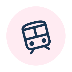 Stylized icon of a train or subway car with a rounded front and windows, on a pink circular background.