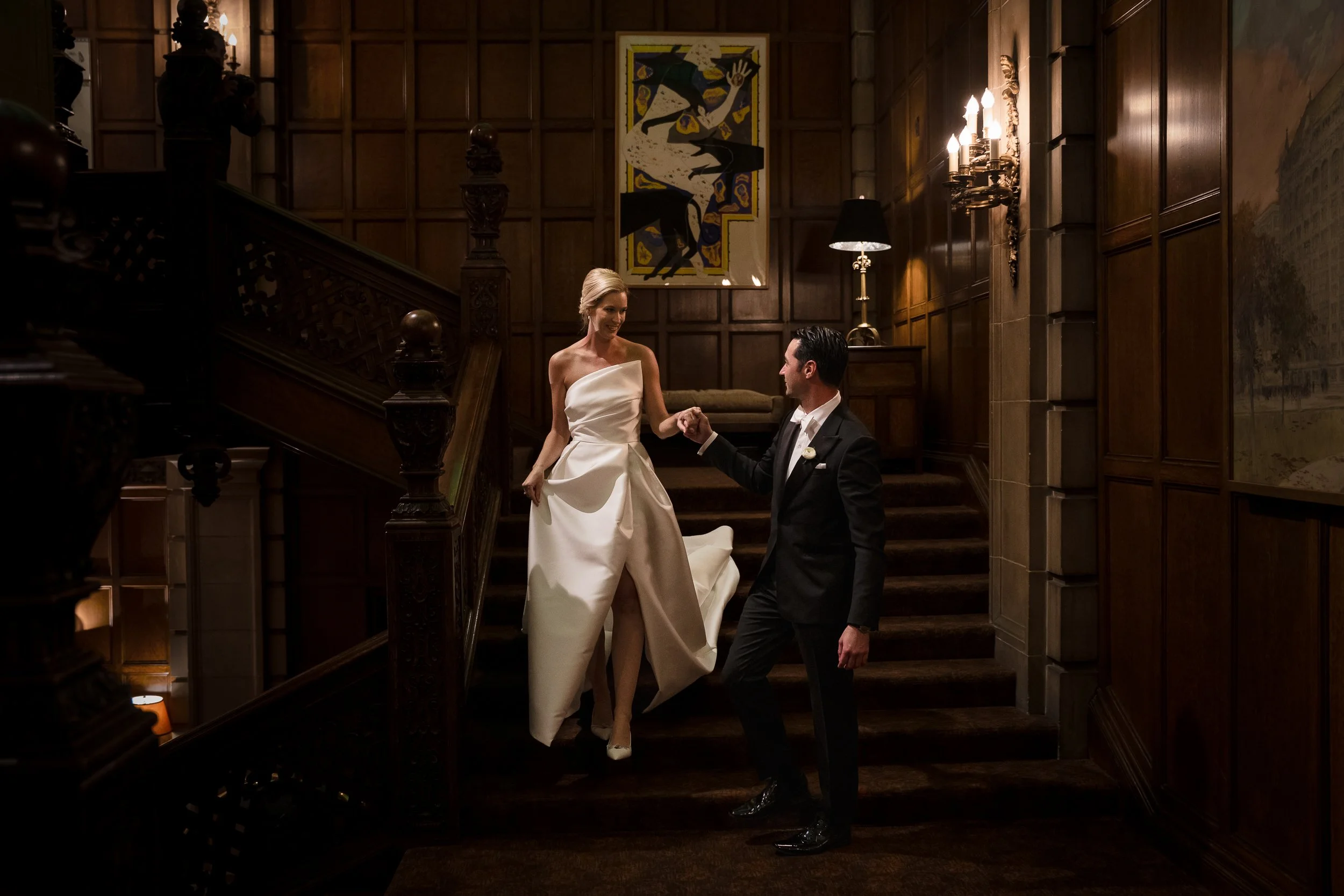 A Groom guides his Bride down the stairs at the Chicago Athletic Club on the way to their Chicago Wedding Reception.