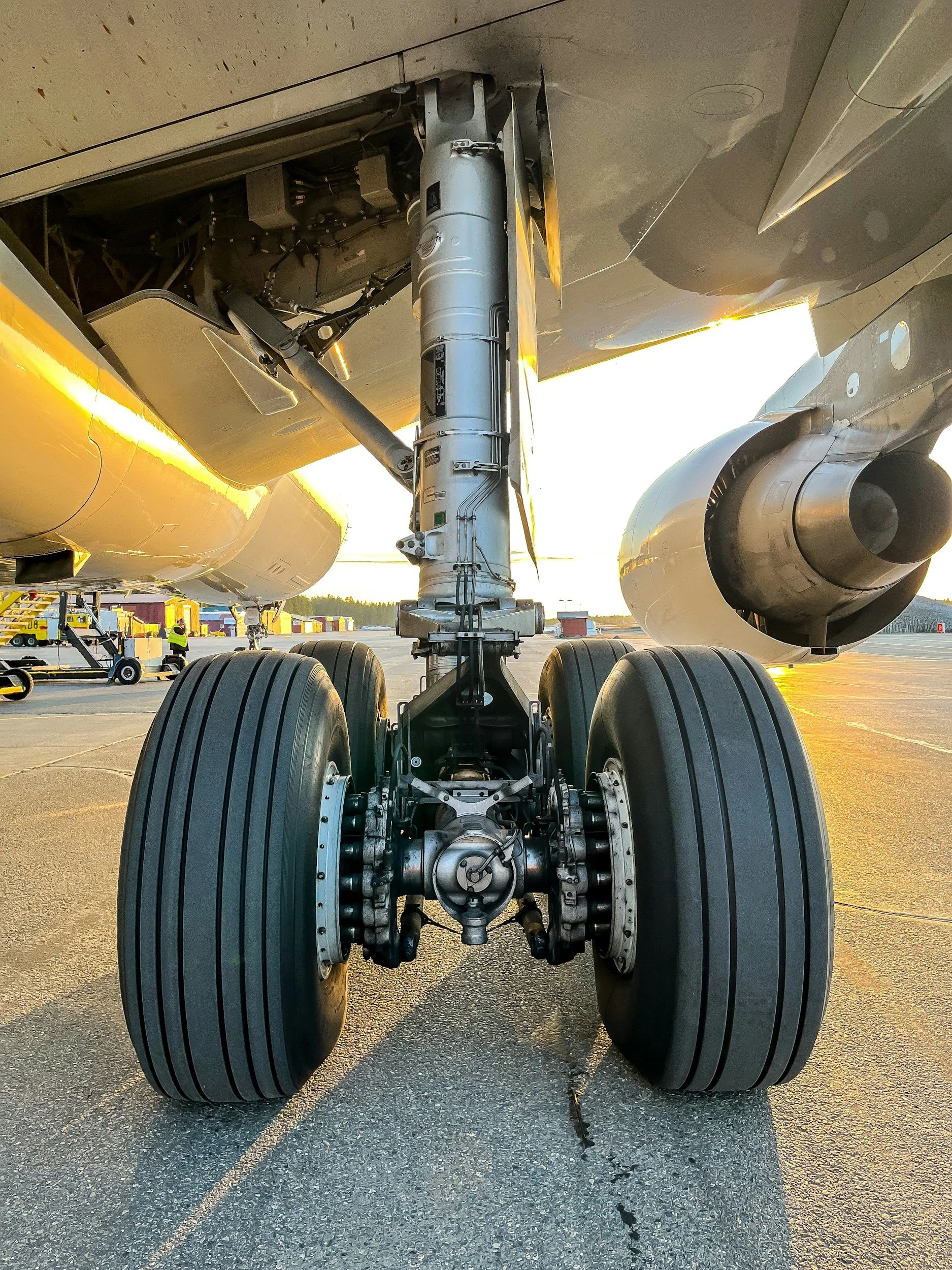 Close-up view of the landing gear and wheels of an aircraft on the tarmac during sunset.