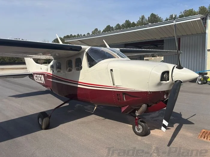 Small single-engine airplane with a white and red color scheme parked on a tarmac.