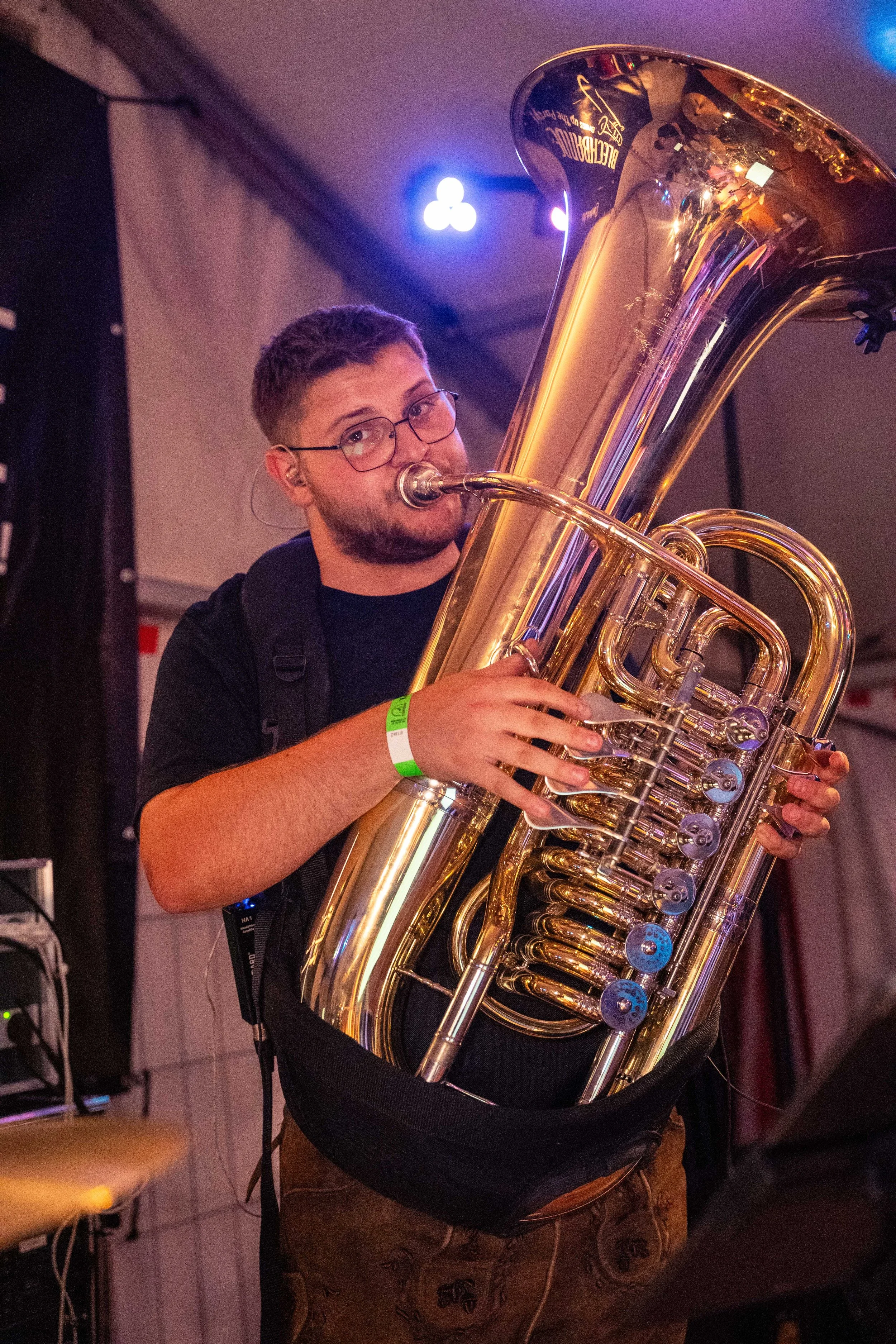 Junge Person spielt Tuba bei einem Auftritt, trägt ein schwarzes T-Shirt.