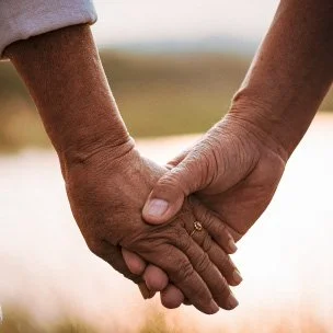 Duas mãos entrelaçadas segurando-se, simbolizando conexão e carinho.