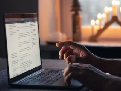 Pessoa usando um laptop em um ambiente interno com velas acesas ao fundo.
