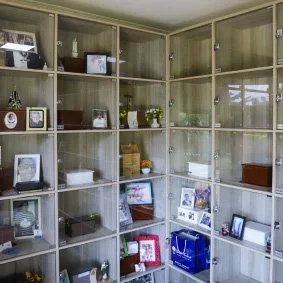 Estante de vidro com vários objetos decorativos e eletrônicos