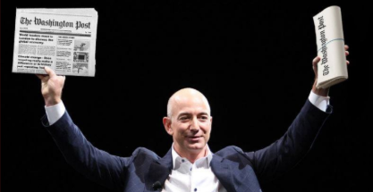 jeff bezos holds up two copies of The Washington Post