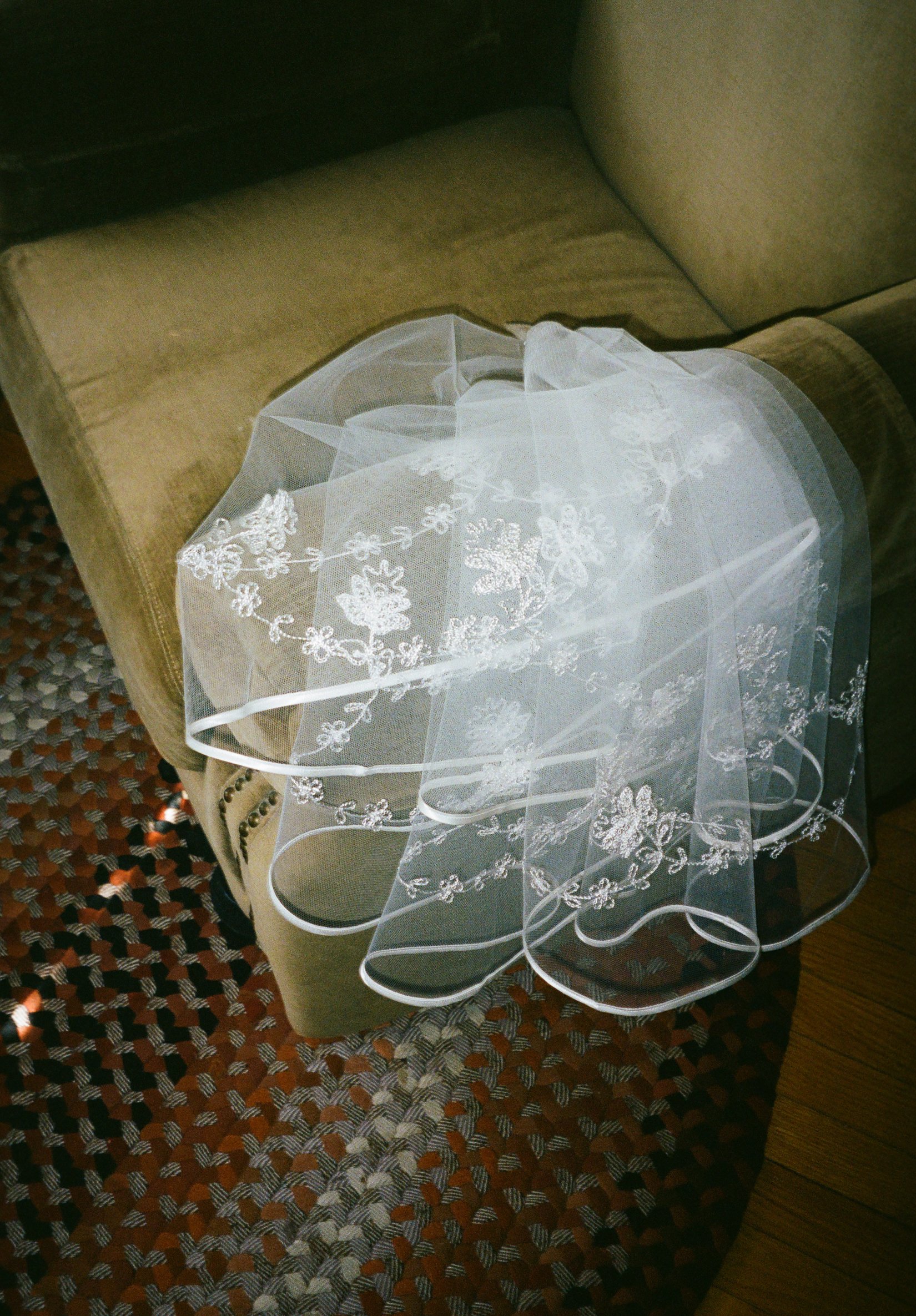 Veil lays on green couch getting ready. Bride and Groom get married at Lincoln Park Conservatory and Salvatores. Grace Coudal is a Chicago lesbian photographer specializing in portraits, candid, editorial, documentary, events, + weddings. Analog film