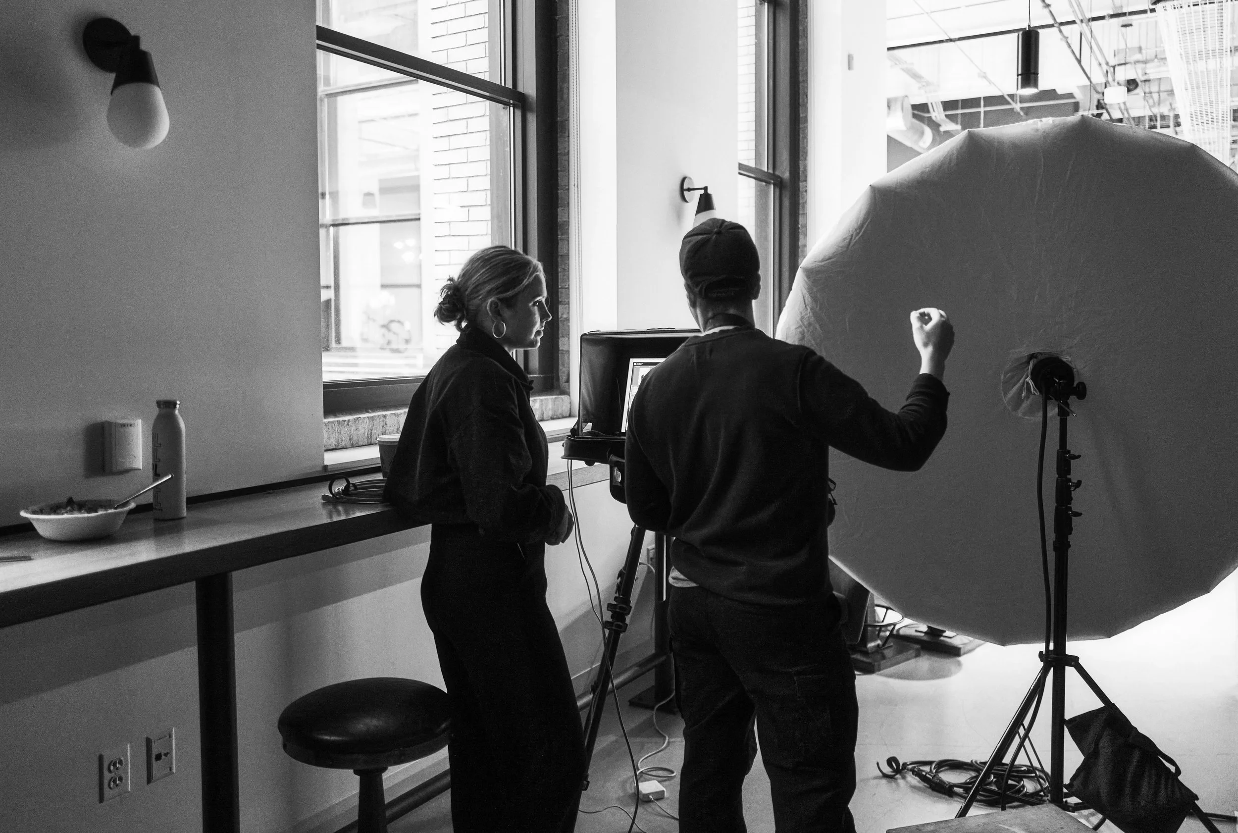 Black and white behind the scenes photos of Grace Coudal on set. She is a Chicago lesbian photographer specializing in portraits, product, food, lifestyle, events, + weddings. Analog film photography, queer-owned.