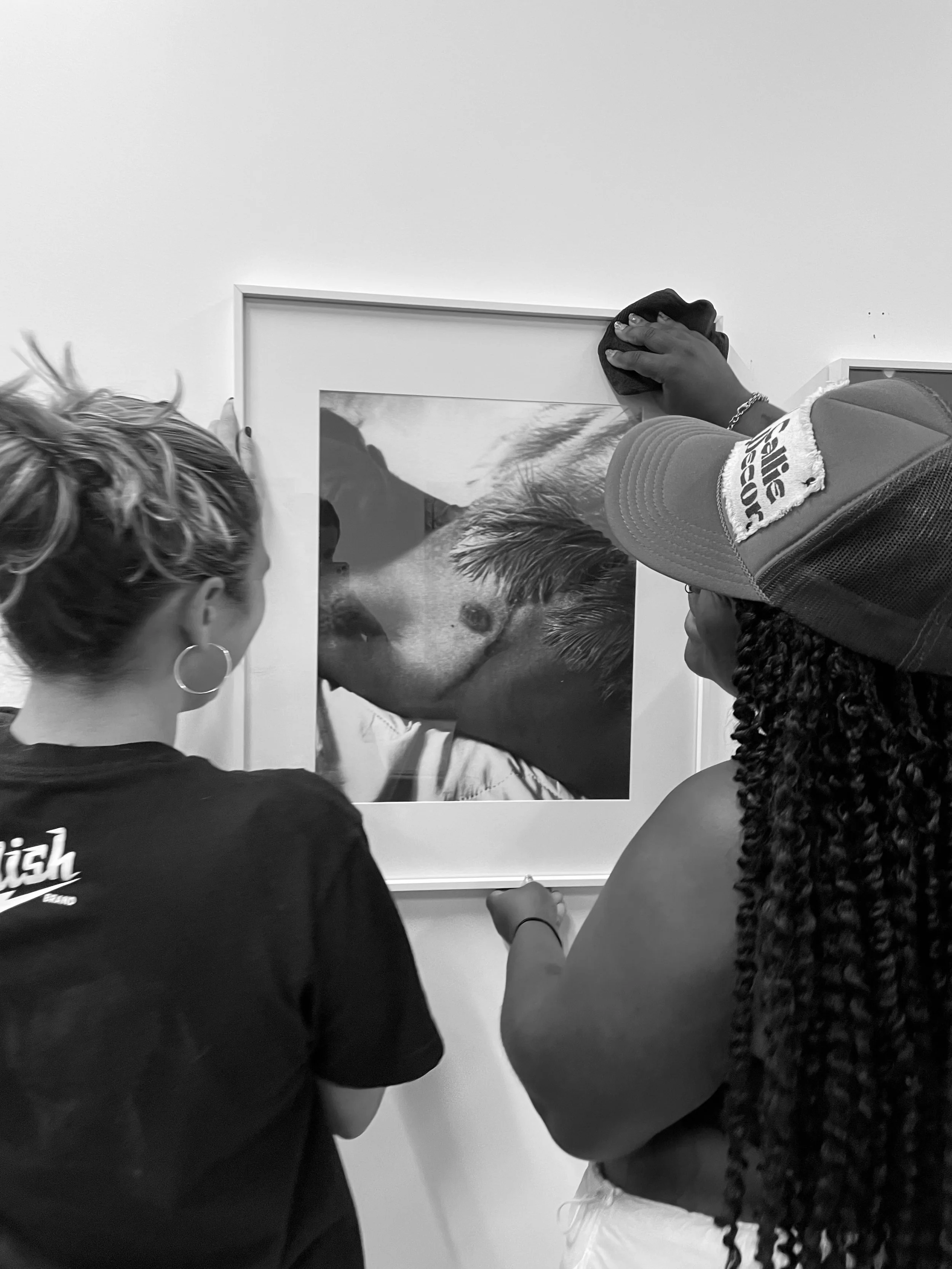 black and white candid photo of weddings by grace hanging fine art exhibition at latitude chicago. Luxury, high-end wedding photographer shot on film. Weddings by grace is a Chicago lesbian queer photographer specializing in portraits, candid, editor