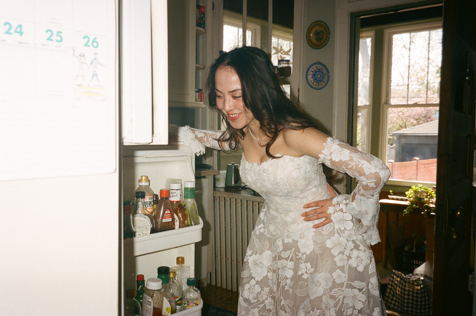 bride, mary, gets something to eat out of fridge while getting ready. Bride and Groom get married at Lincoln Park Conservatory and Salvatores. Grace Coudal is a Chicago lesbian photographer specializing in portraits, candid, editorial, documentary, e