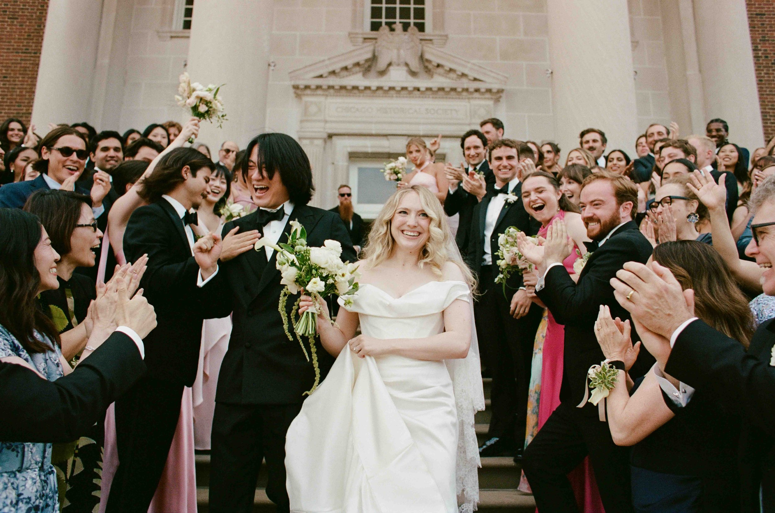 Bride and groom get married at the Chicago History Museum, with creative, lively wedding focused on community, family, laughter. Documentary and candid photos on analog nostalgic film. Weddings by Grace is a Chicago lesbian queer luxury wedding photo