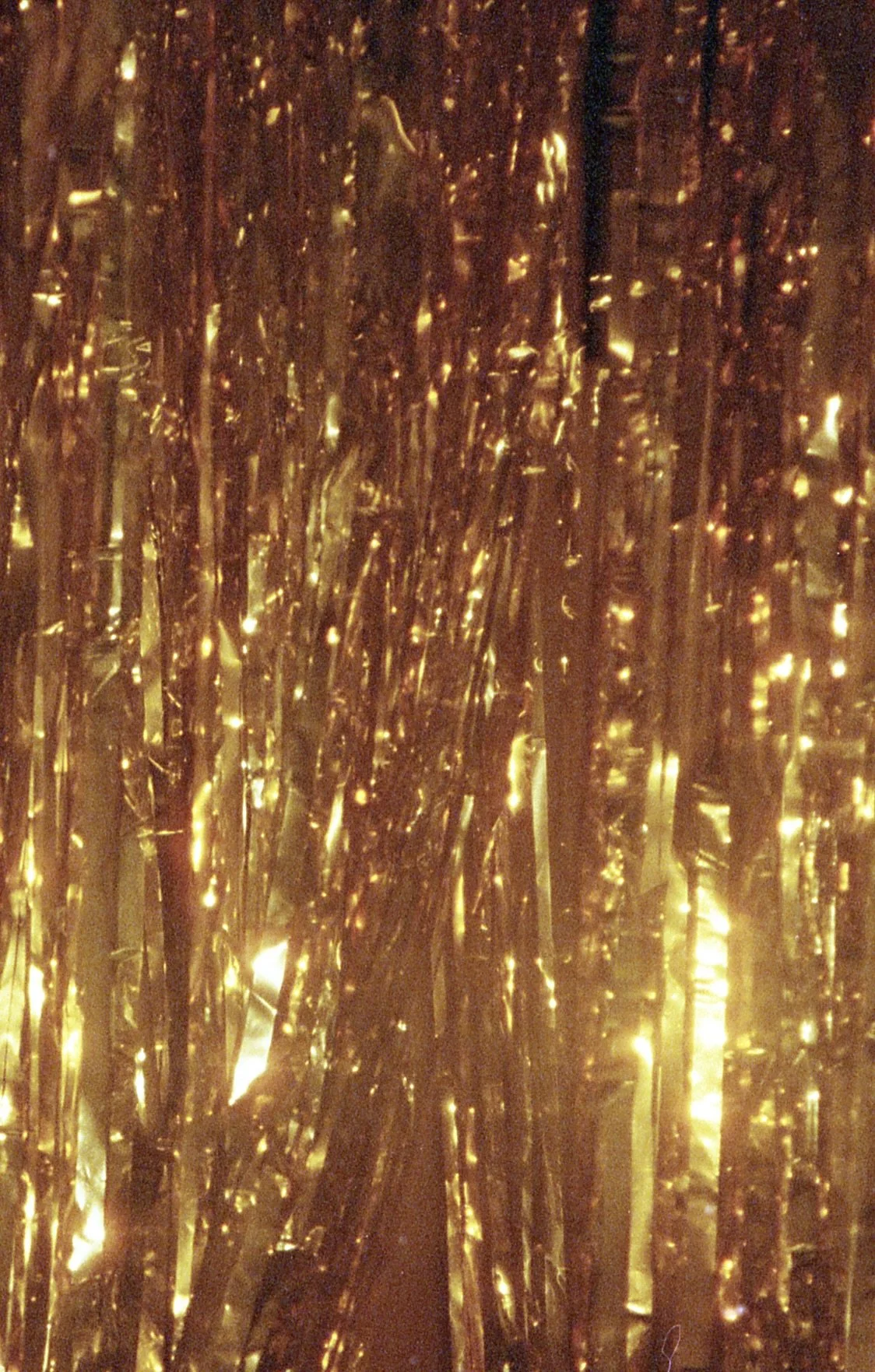 Golden metallic tinsel curtain with reflective strands and lights.