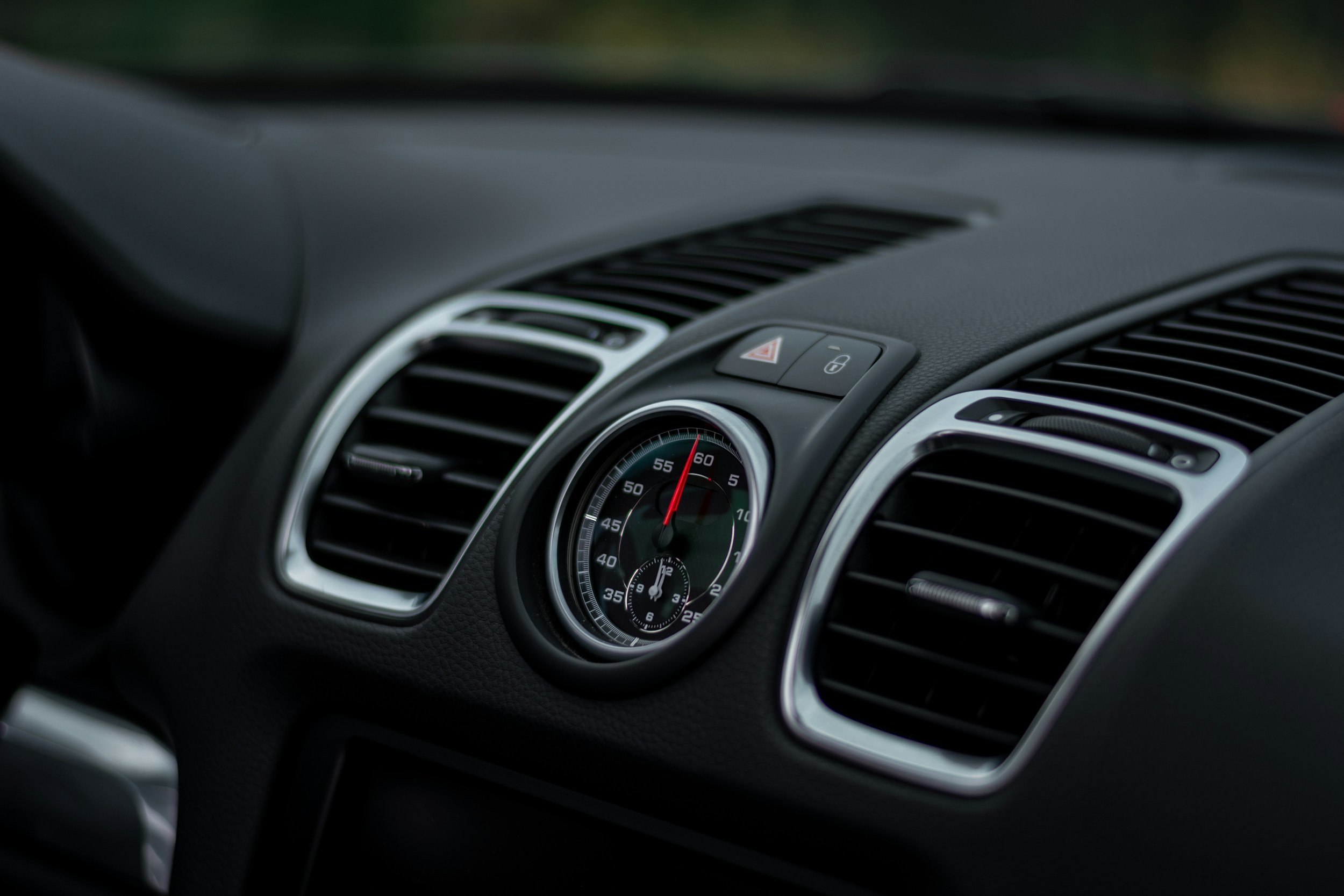 Close-up of a car dashboard showing an analog clock and air vents.