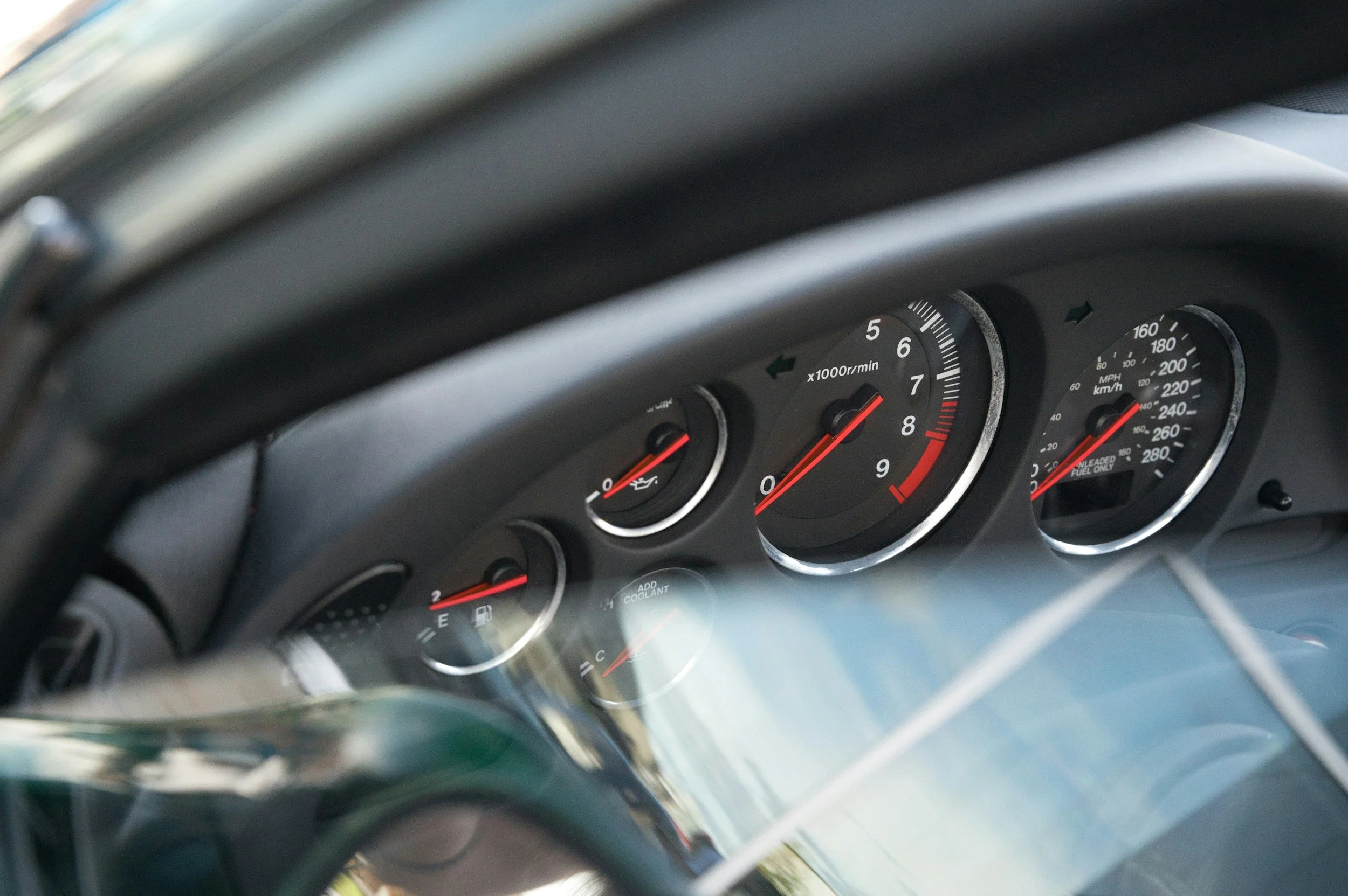 Close-up photo of a car's instrument cluster, showing the speedometer, tachometer, and fuel gauge with black dials and white markings.