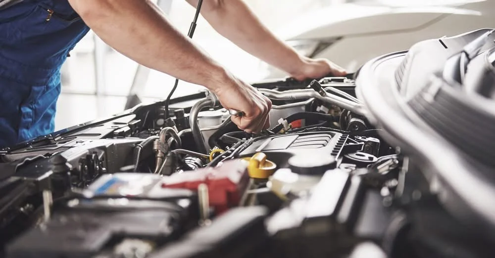 A mechanic working on a car engine in a garage.