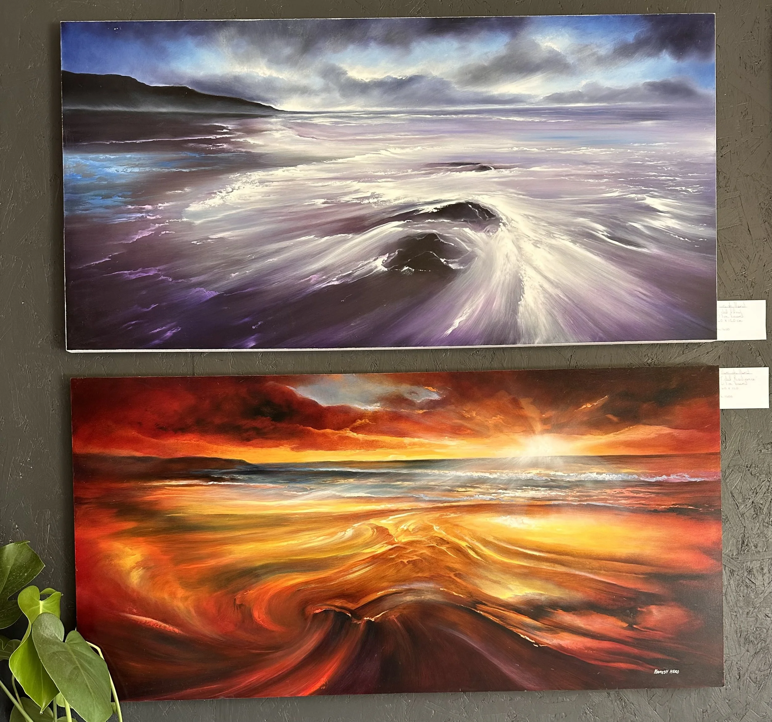 Two paintings of ocean scenes, one with stormy purple waves and the other with fiery sunset over the water.