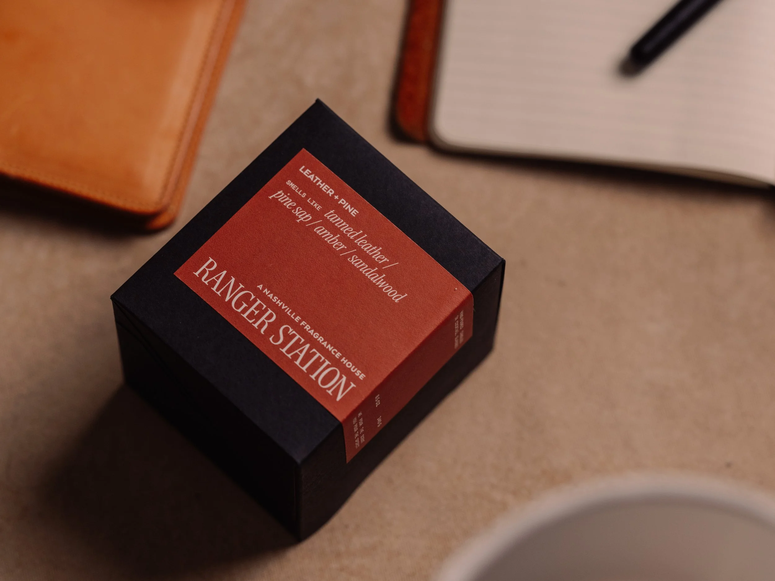 Product photography -- Black box of an Nashville fragrance house candle with a red label that says 