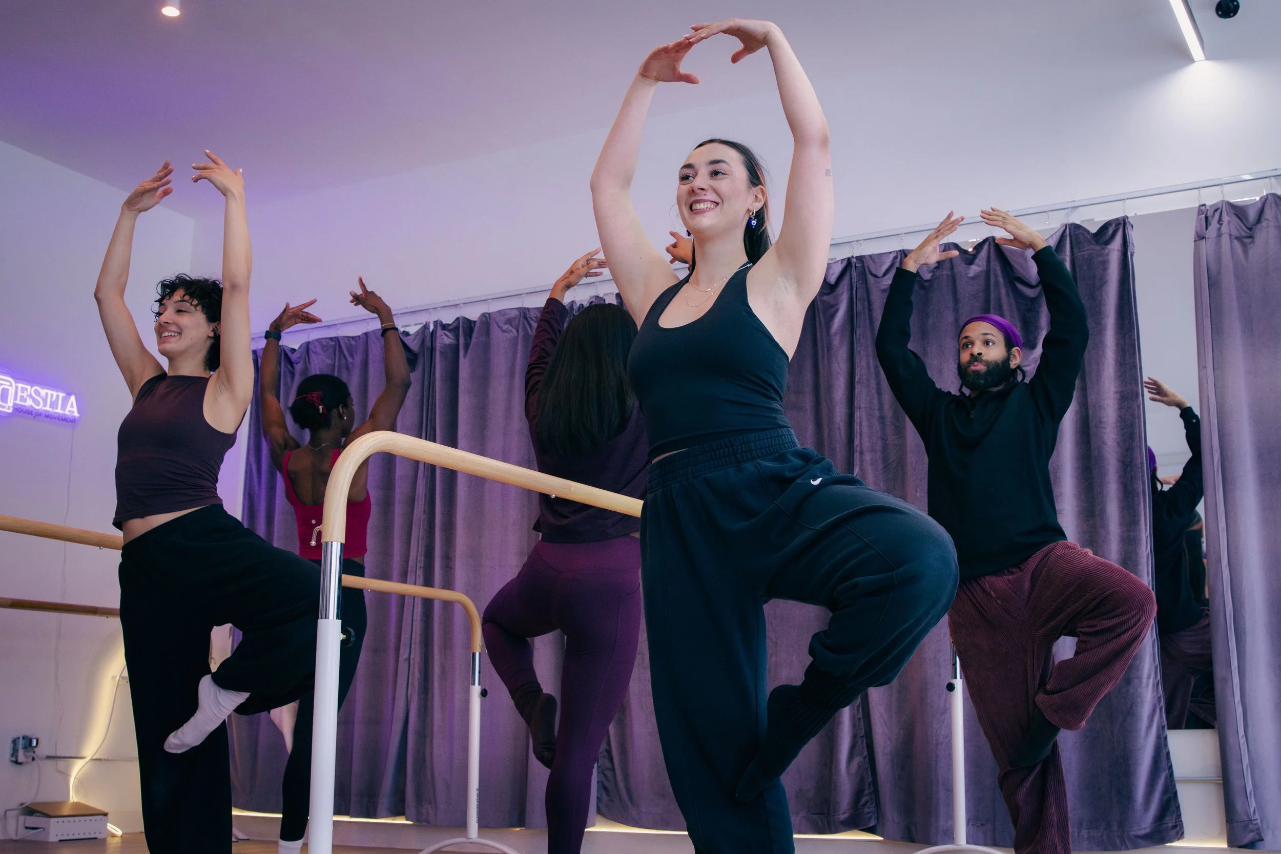 Adults practicing barre exercises during a fitness class at ESTIA House of Movement.