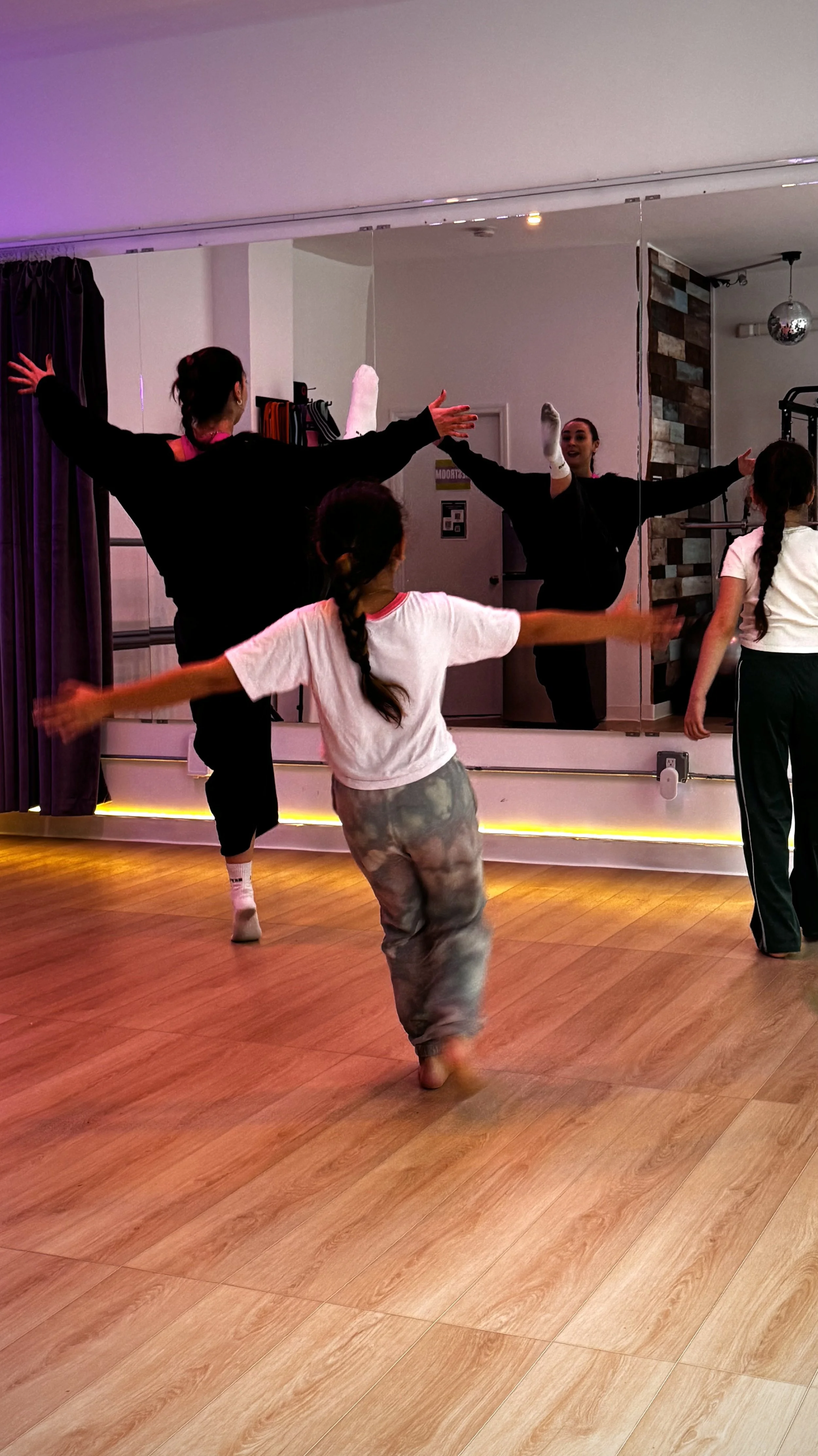 Dance instructor leading children through a stretching exercise during a dance class at ESTIA House of Movement.