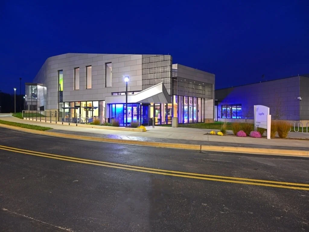 Modern building with glass and metal exterior, illuminated at night.