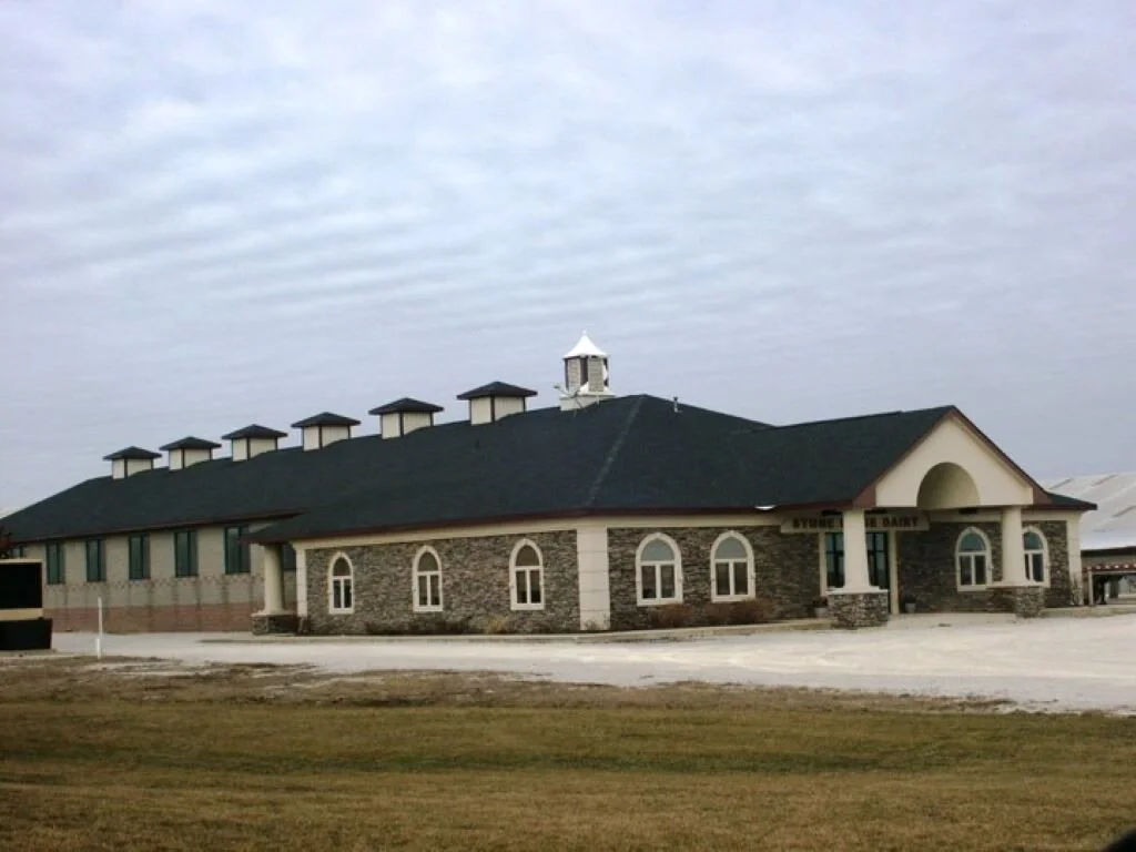 A large building with stone and brick exterior, multiple windows, and a pitched roof with several small chimneys; the building has a cupola and a covered entrance. It appears to be a storage or library building.