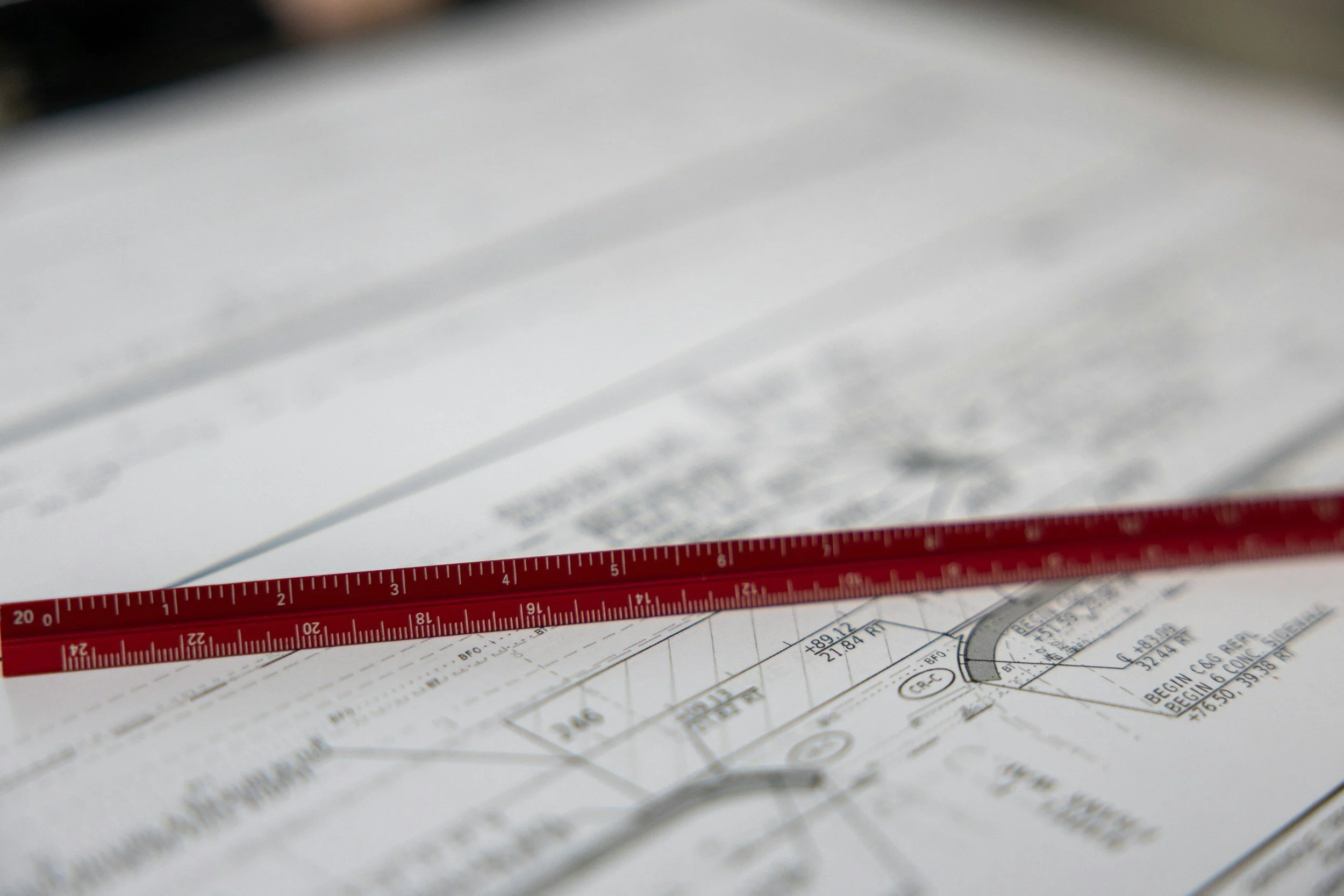 Architectural or engineering drawings with a red measuring scale placed on top.