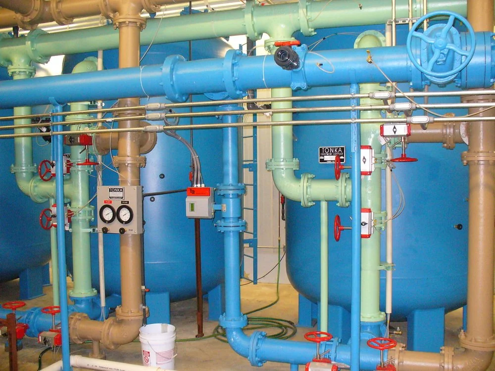 Industrial piping system with various colored pipes, valves, and gauges.