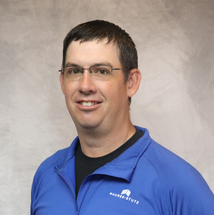 A man with short dark hair and glasses wearing a blue jacket with 'Mauer Stutz' logo, smiling at the camera against a plain background.