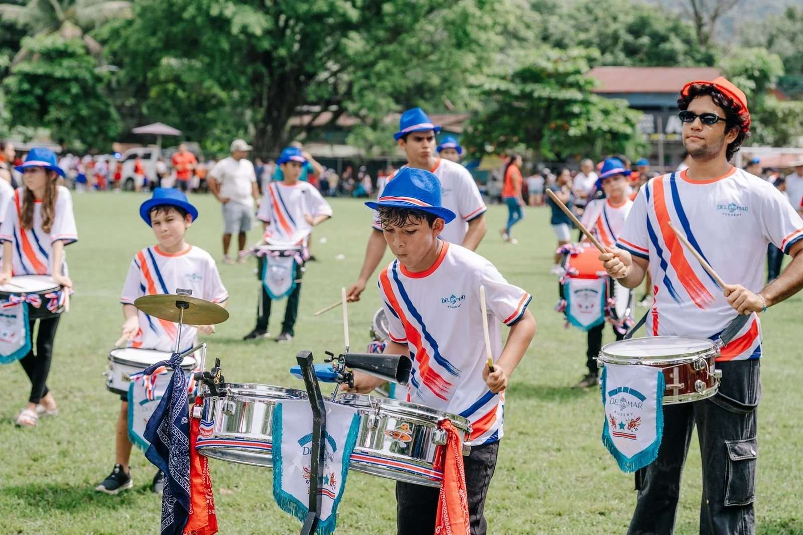 A group of students in red outfits and Santa hats participating in a holiday parade in Nosara Costa Rica as part of the marching band for Del Mar Academy school