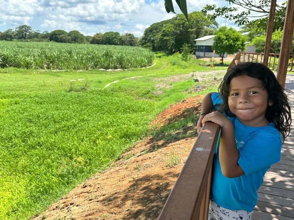Kindergarten student smiling in front of vast green field during a school field trip in Nosara Costa Rica