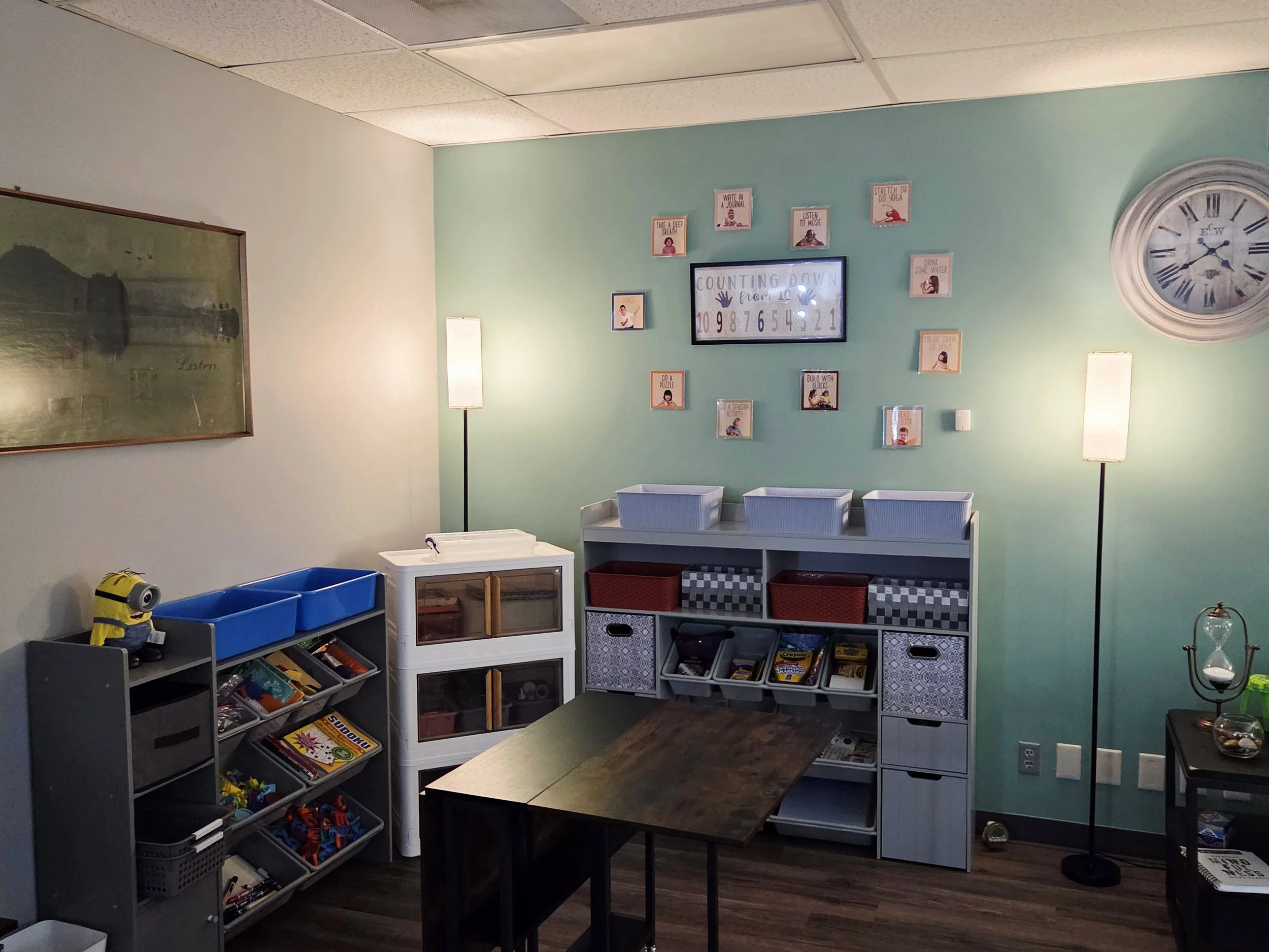 Scenic landscape with a large body of turquoise water, green rolling hills, and rugged mountains with cloudy sky in the background.