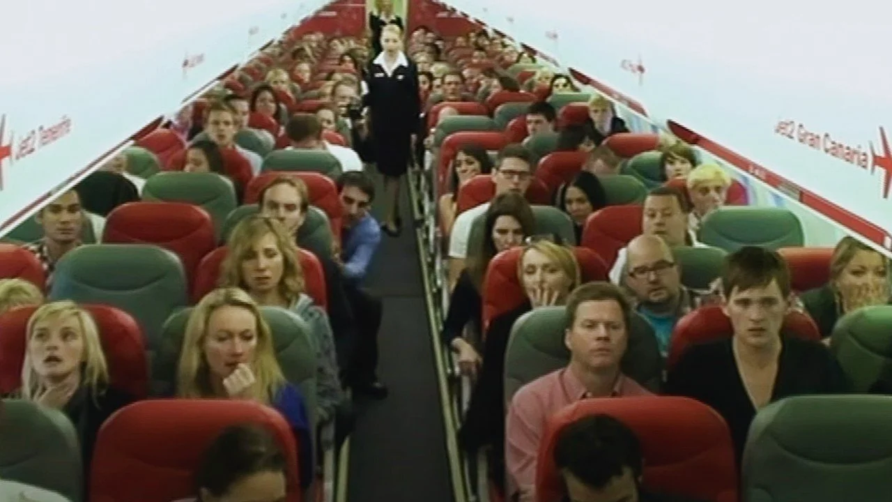 Actor Ian Prosser with other passengers sitting onboard a plane in a scene from the TV programme Hero at 30000 feet with Derren Brown.
