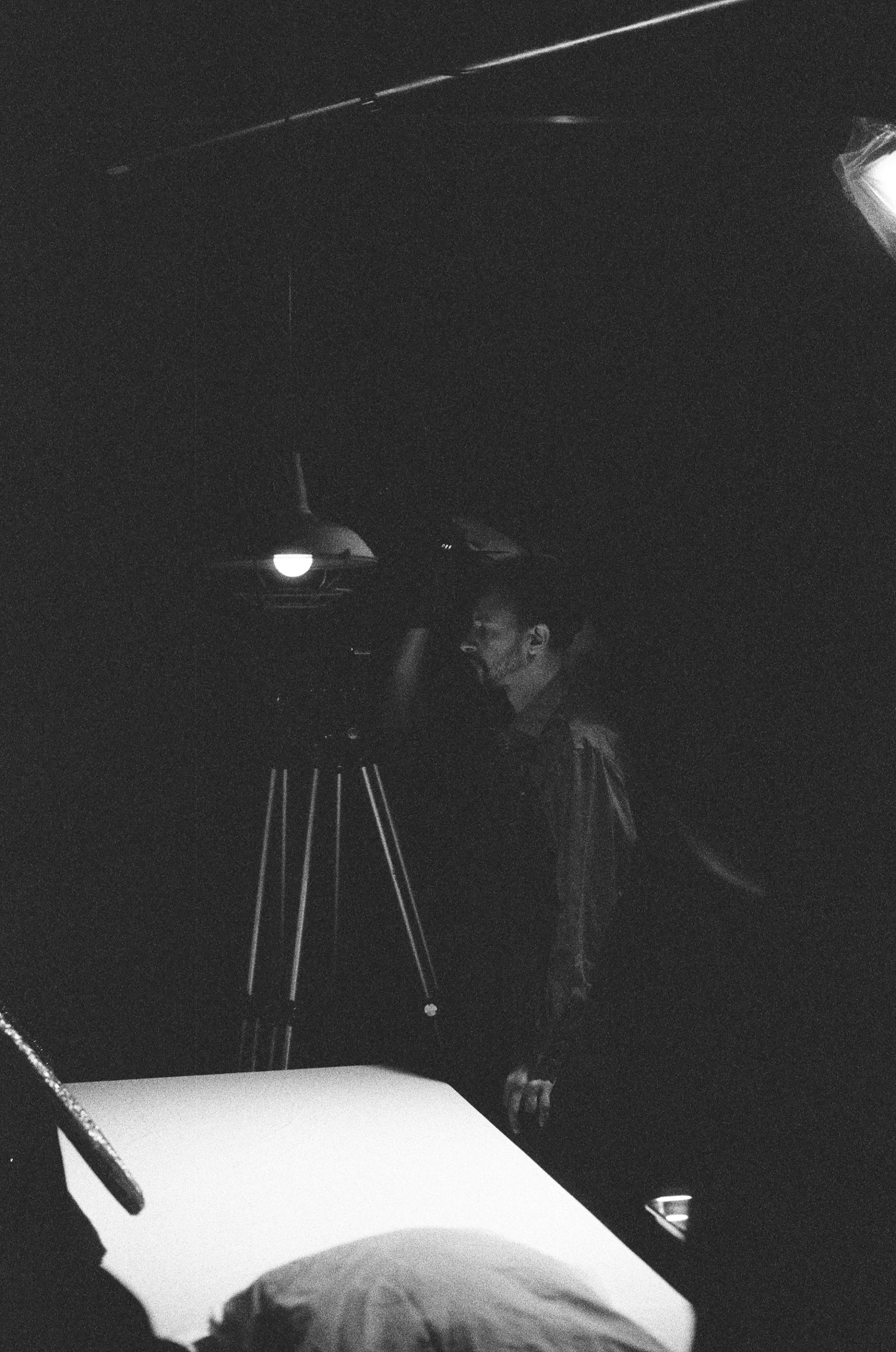 Black and white photo of a man looking into a large camera or film camera, with a dark background.