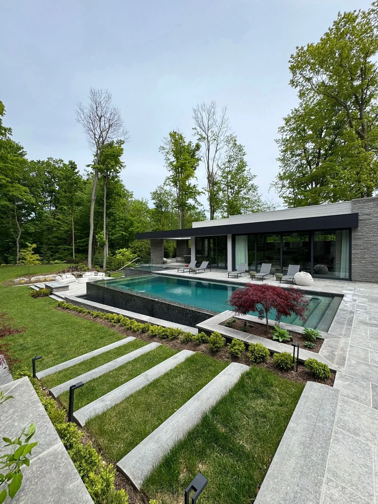 Modern backyard landscaping with custom Ottawa Platinum limestone steps and pool coping, showcasing luxury outdoor stonework and architectural-grade natural stone