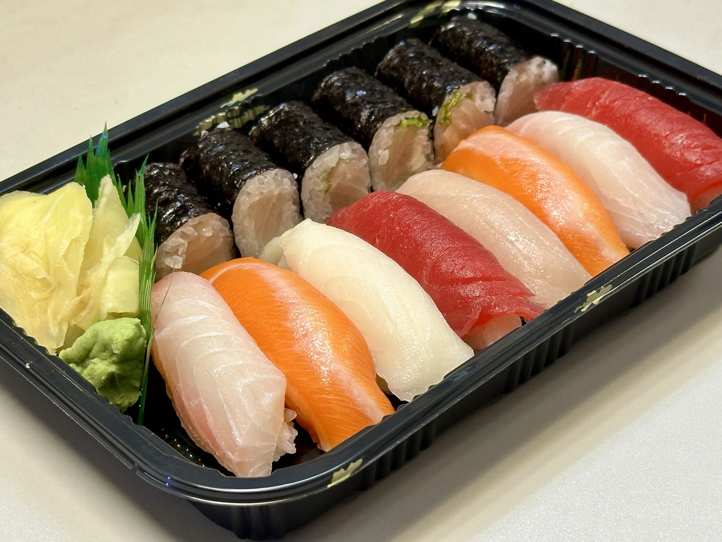 Assorted sushi platter with nigiri, maki rolls, wasabi, and pickled ginger.