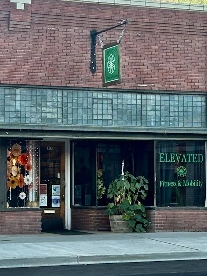 Outside of a fitness and mobility center named Elevated, featuring a green sign with a flower emblem