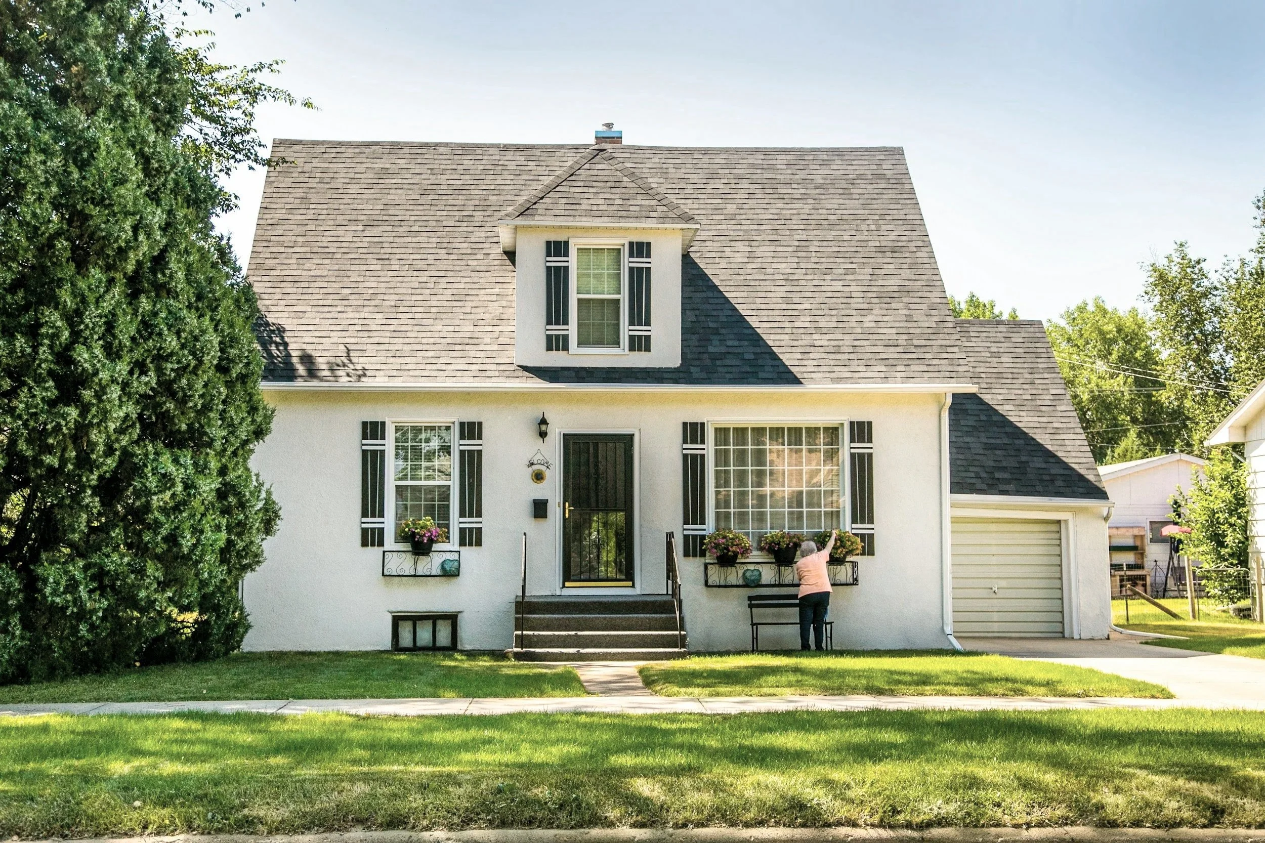 Front view of a two-story white house with black shutters, a black front door, steps leading up to it, and a grass lawn on Possum Kingdom Lake. Kemp Co. Home Services providing their Home Management solutions to this client.