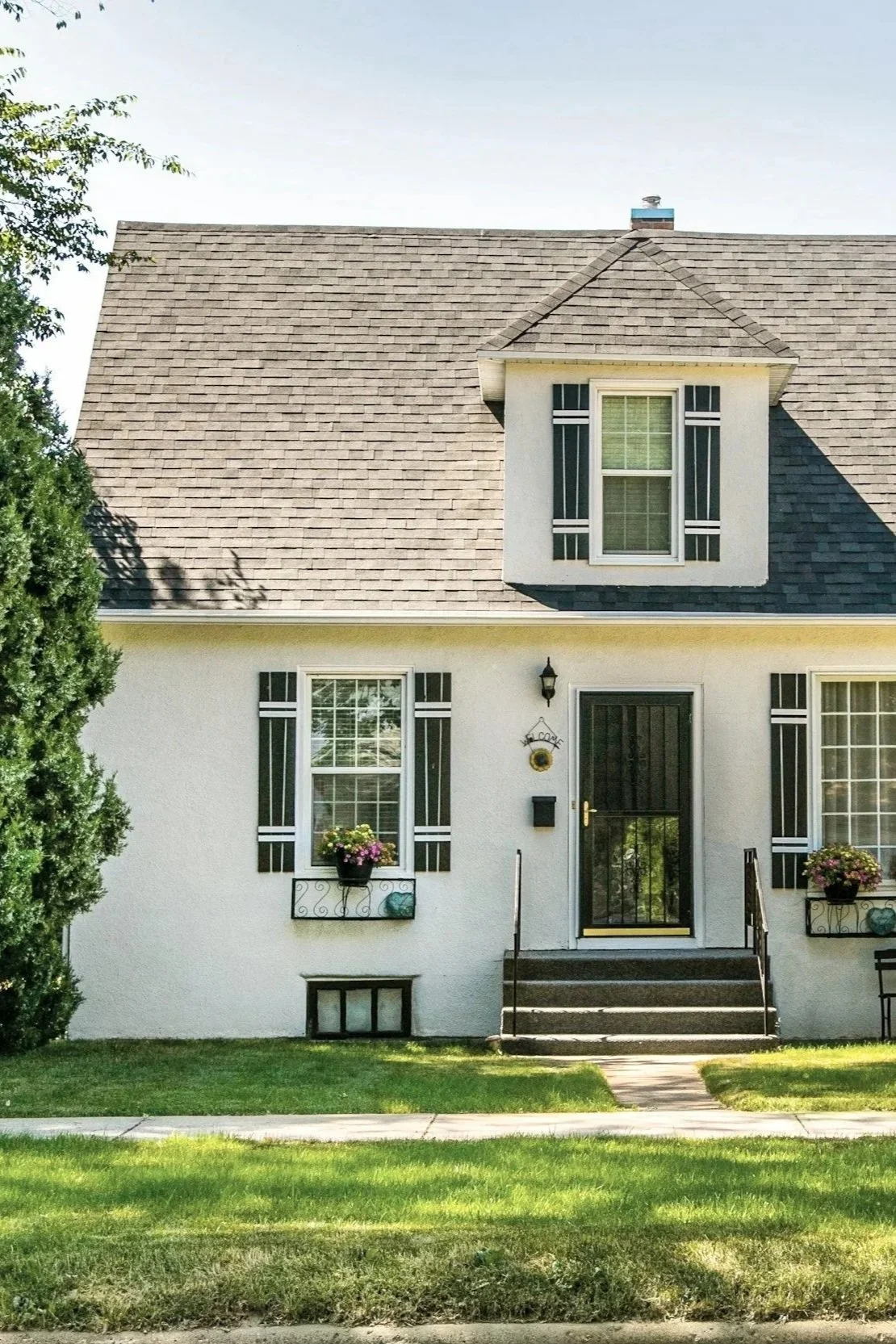 Front view of a two-story white house with black shutters, a black front door, steps leading up to it, and a grass lawn on Possum Kingdom Lake. Kemp Co. Home Services providing their Home Management solutions to this client.