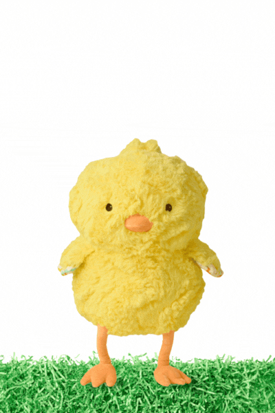 A plush yellow chick toy with orange beak and feet standing on green grass against a white background.