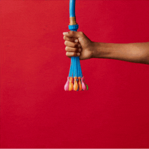 A person's hand holding a bundle of colorful watering hose nozzles against a red background.