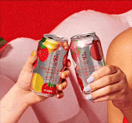 Two people clinking cans of flavored sparkling water against a red and white background.