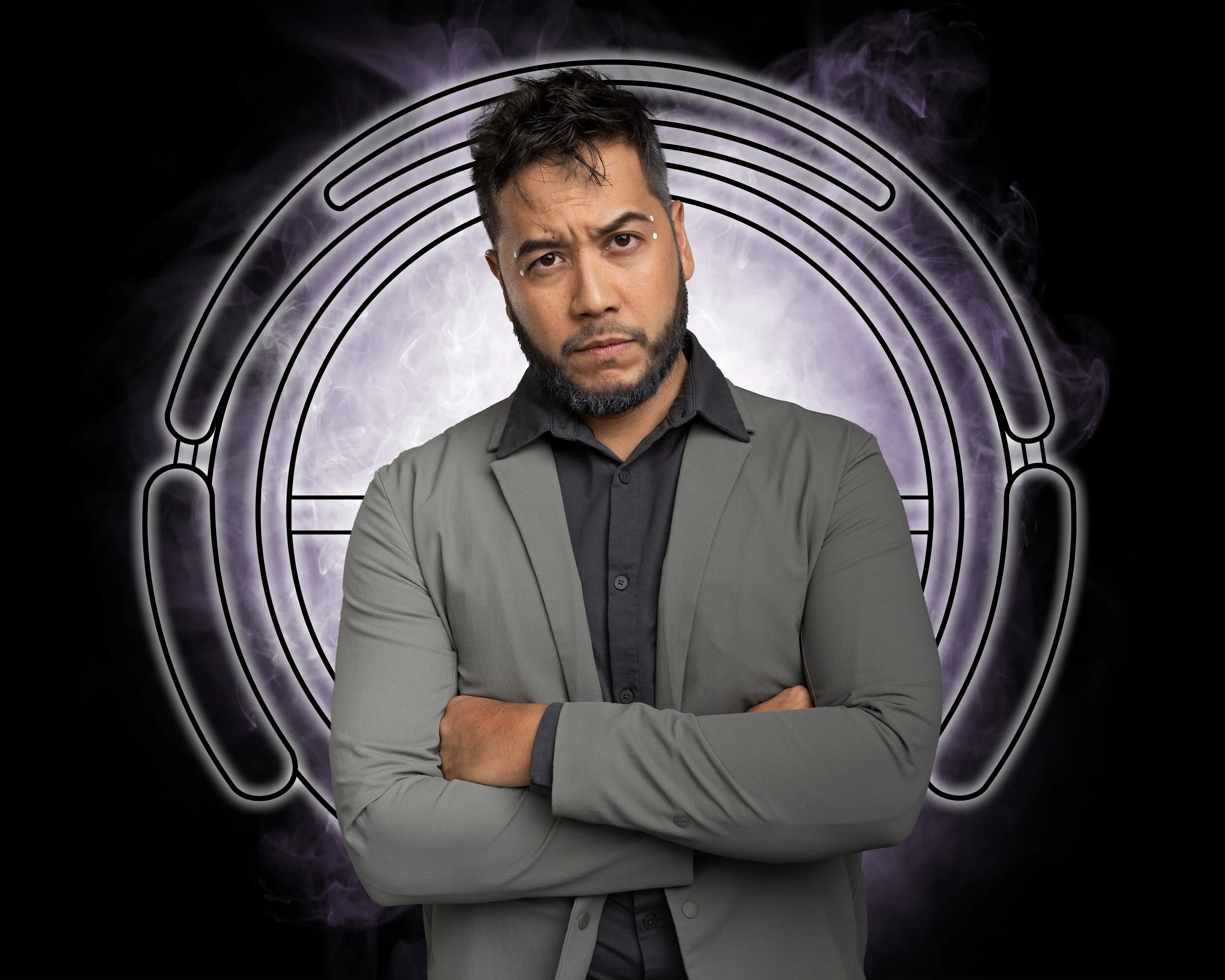 Portrait of Maestro, a man with his arms crossed staring intently at the camera.