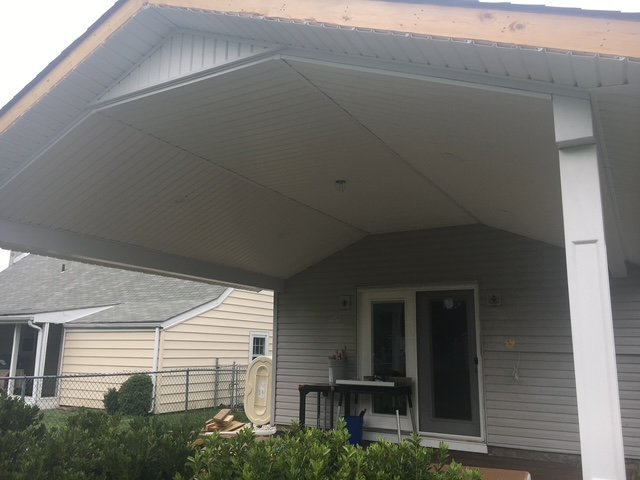 Backyard patio area with sliding glass door, small outdoor table, and porch roof overhang.