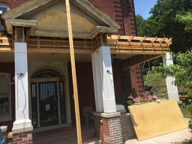 Front porch of a brick house under construction with wooden framing and temporary support beams