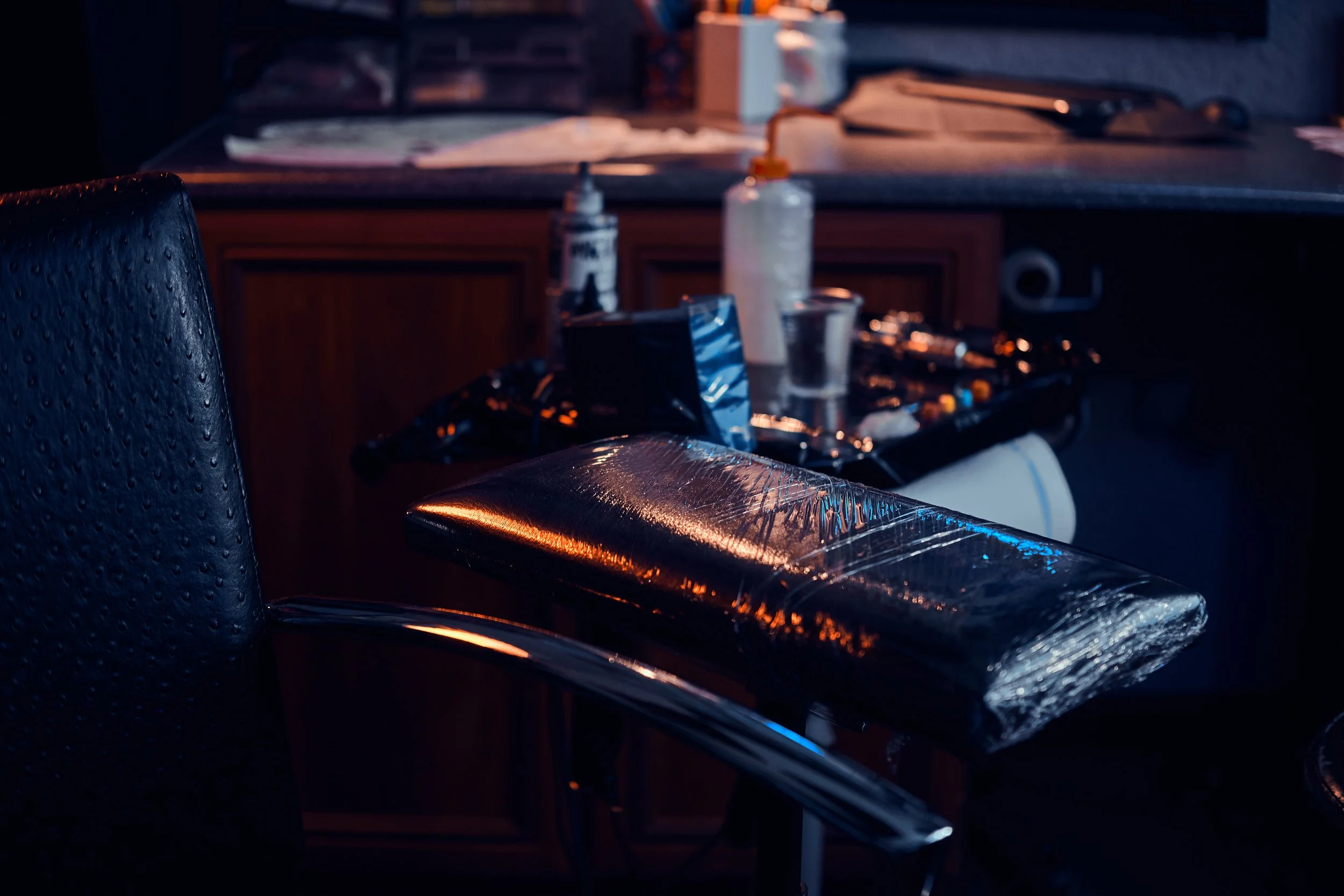 Tattoo machine and equipment in a dimly lit studio setting.