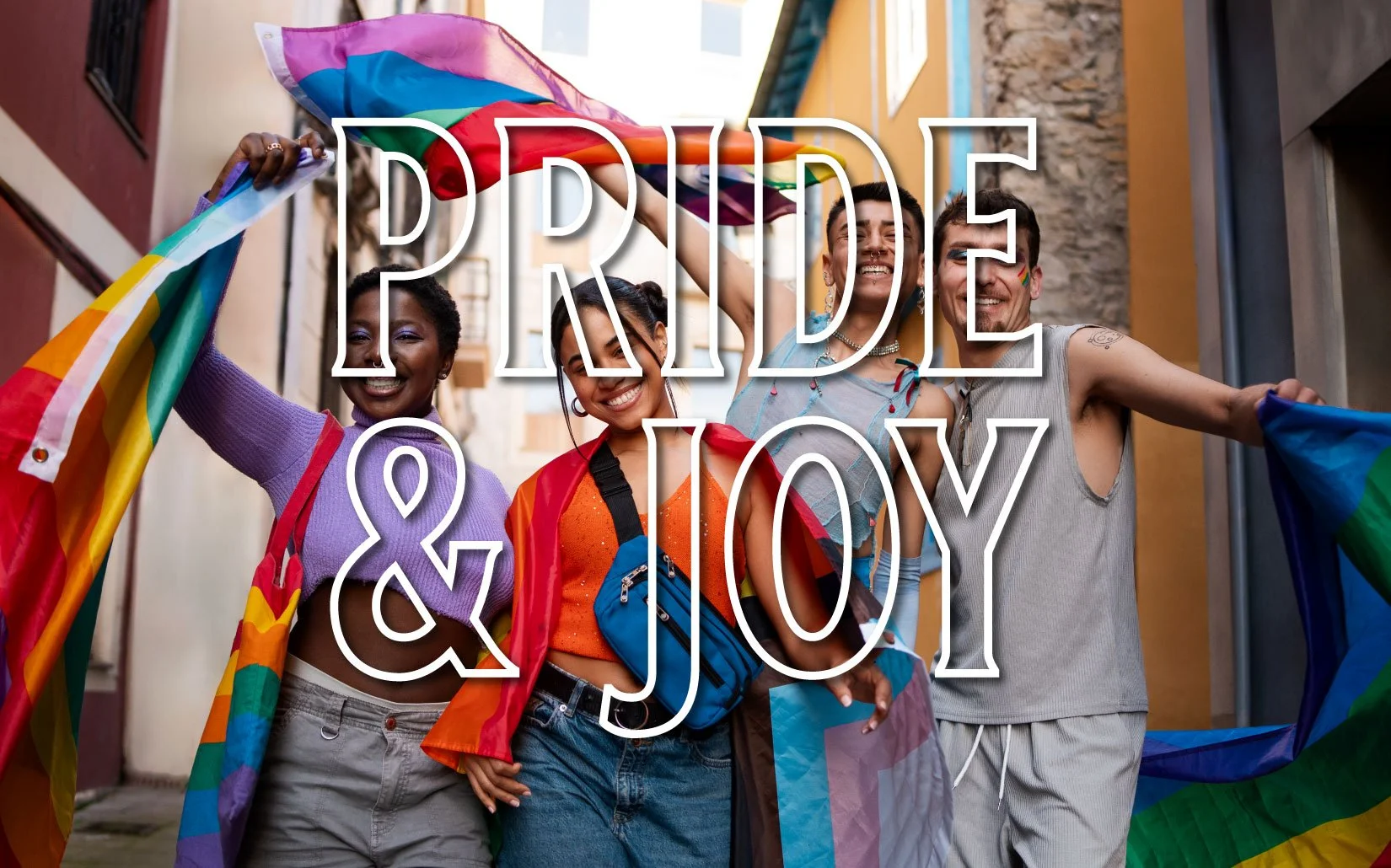 Four smiling people of varying skin tones wave rainbow pride flags on a city street. Text overlay reads "Pride & Joy."