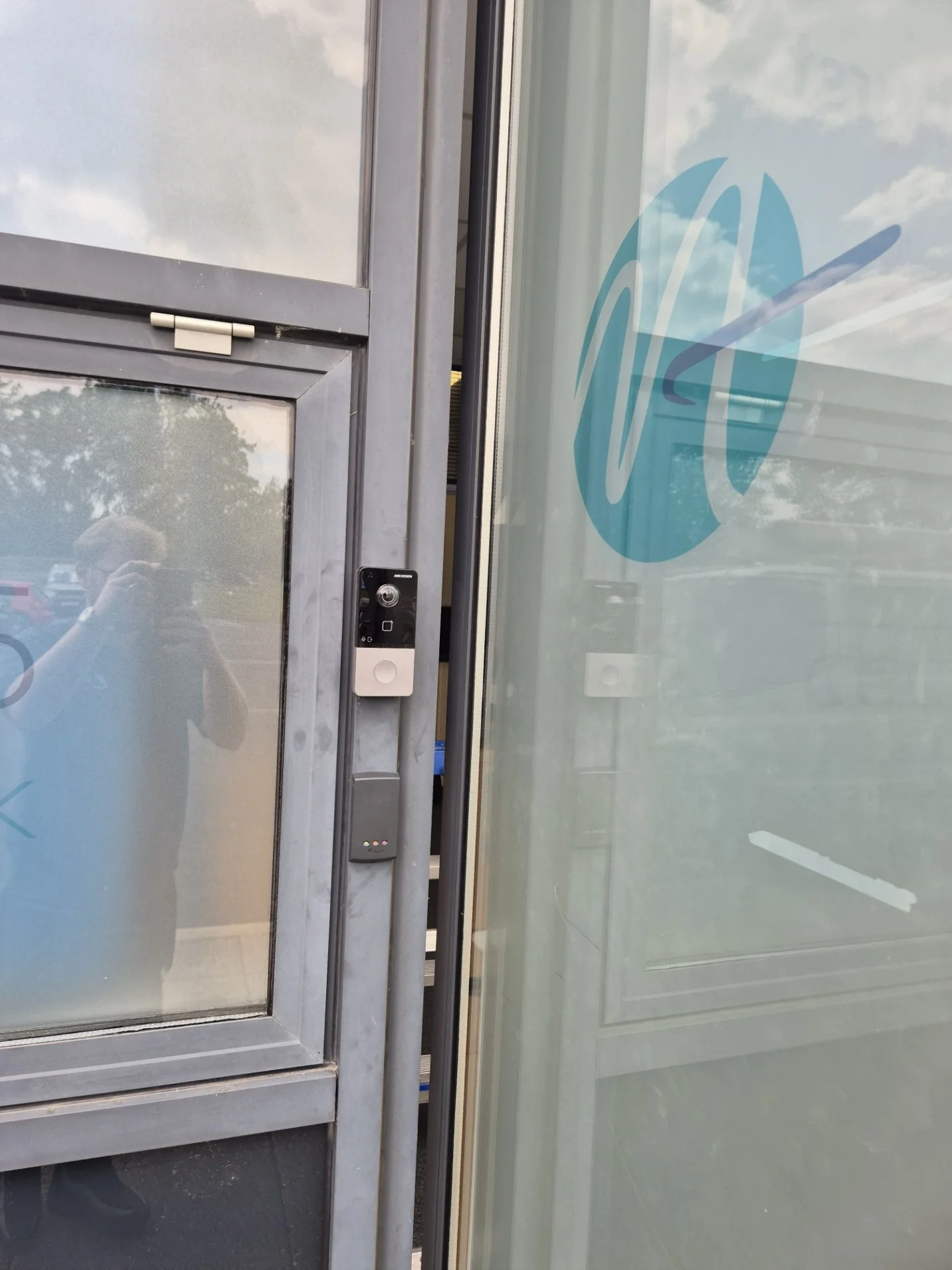 Close-up of a glass door with an access control device and an intercom.